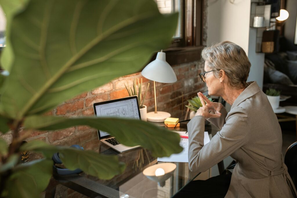 “Older woman creating digital products on laptop at home”